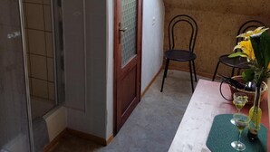 A room with a sloped ceiling, a wooden door, a small table with a vase and a bottle, and a chair. - Large apartment (92 sqm) "sea eagle" 1-6 people in a great location (Kargow)