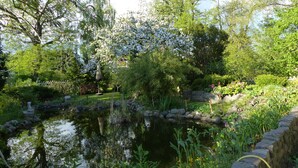 A serene garden with a pond, surrounded by lush greenery and flowering trees. - Large apartment (92 sqm) "sea eagle" 1-6 people in a great location (Kargow)