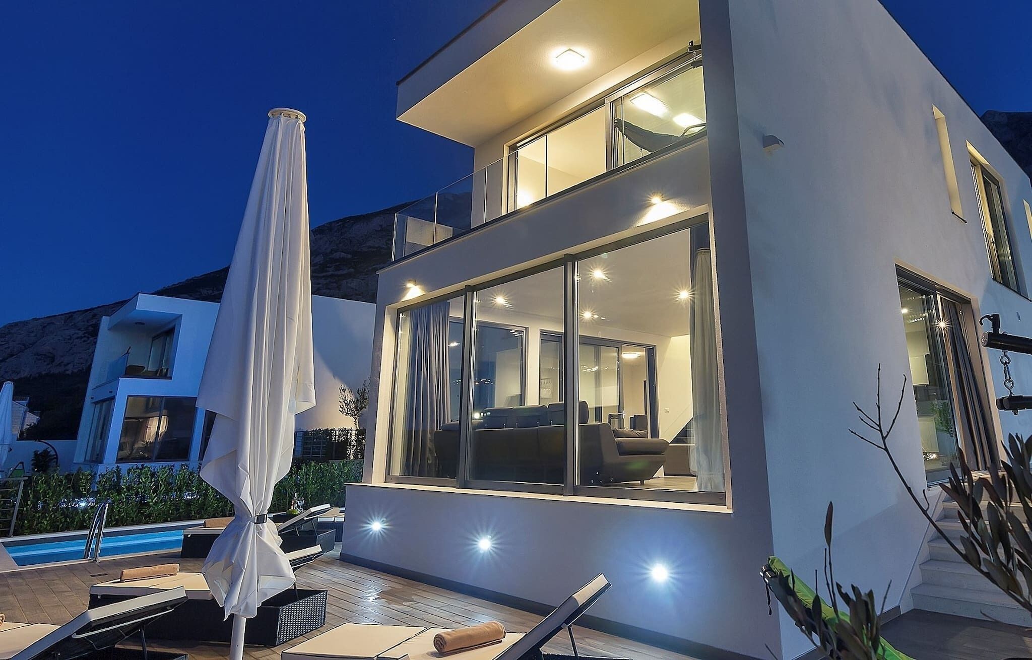 A modern two-story building with large windows, outdoor seating, and a pool area.