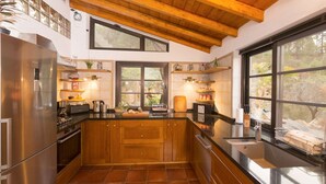 Una cocina moderna con armarios de madera, un refrigerador de acero inoxidable y un amplio ventanal con vistas al exterior.