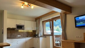 A modern kitchen with white cabinets, a microwave, and a wooden dining table.