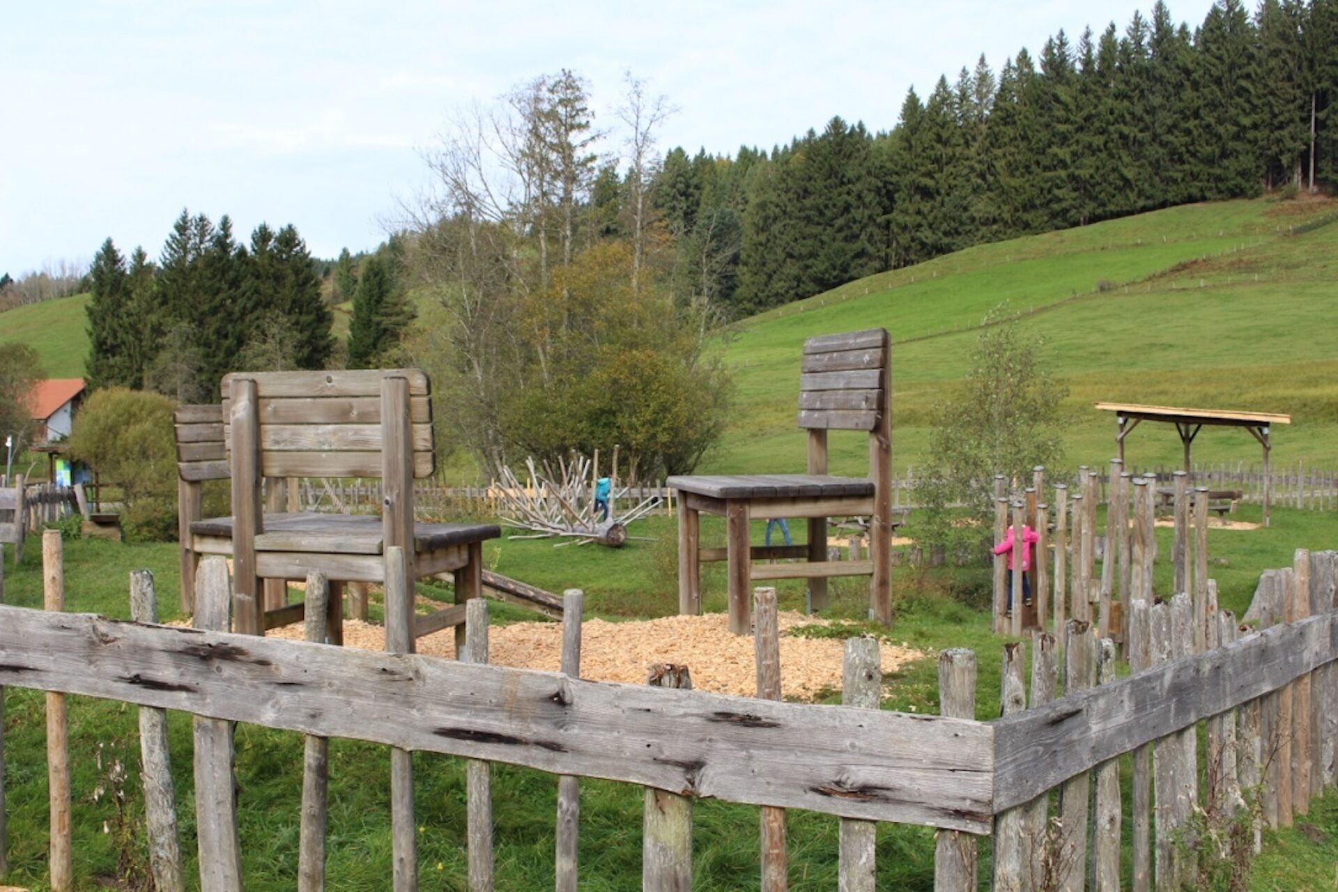 A rustic wooden fence with a bench and a small table in a rural setting.