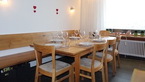A dining area with a wooden table set for four, surrounded by cushioned chairs.