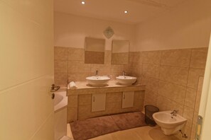Un baño con dos lavamanos, un espejo y un bidé.