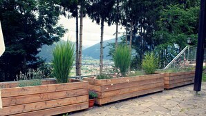 Eine terrasse mit Steinpflasterung und Holz-Pflanzgefäßen, die verschiedene Pflanzen und Blumen enthalten.