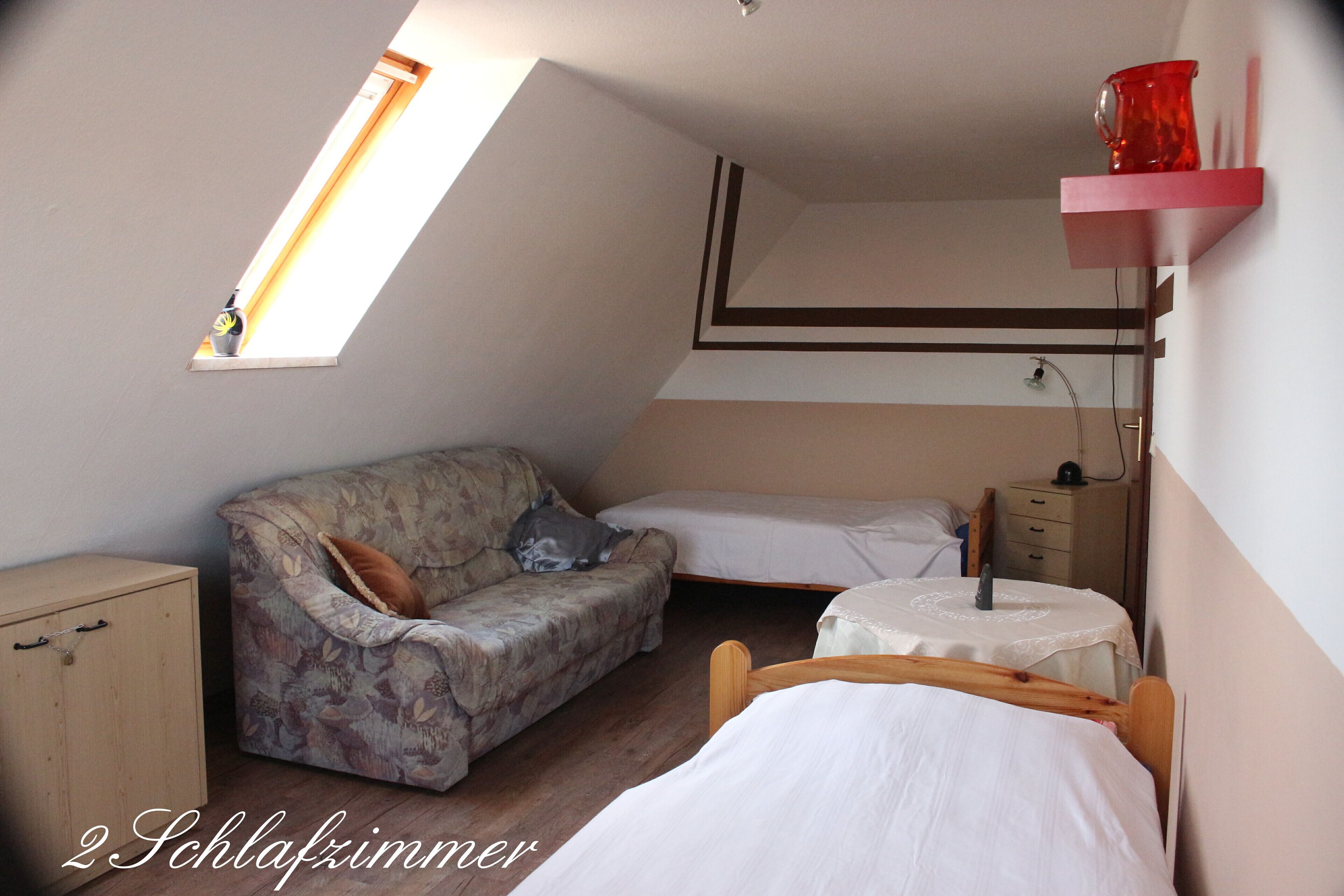 Ein Schlafsaalzimmer mit Hochbett, einer Schlafcouch, einem kleinen Tisch und einem Schrank.