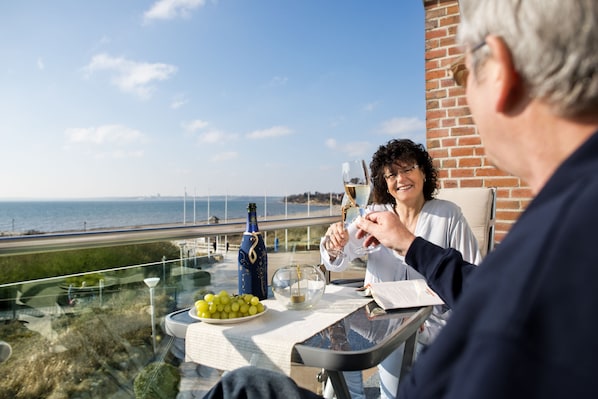 A terrace with a table set for two, a bottle of wine, and a glass of wine.