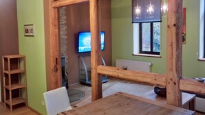 A room with a wooden table and chairs, a television on the wall, and a window with blinds. - Apartment Beta, haven with sauna in an upscale ambience (Weenzen)