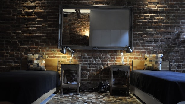 A room with a brick wall, two beds, a mirror, and a small table with lamps. - Apartment Beta, haven with sauna in an upscale ambience (Weenzen)