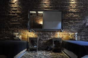A room with a brick wall, two beds, a mirror, and a small table with lamps. - Apartment Beta, haven with sauna in an upscale ambience (Weenzen)