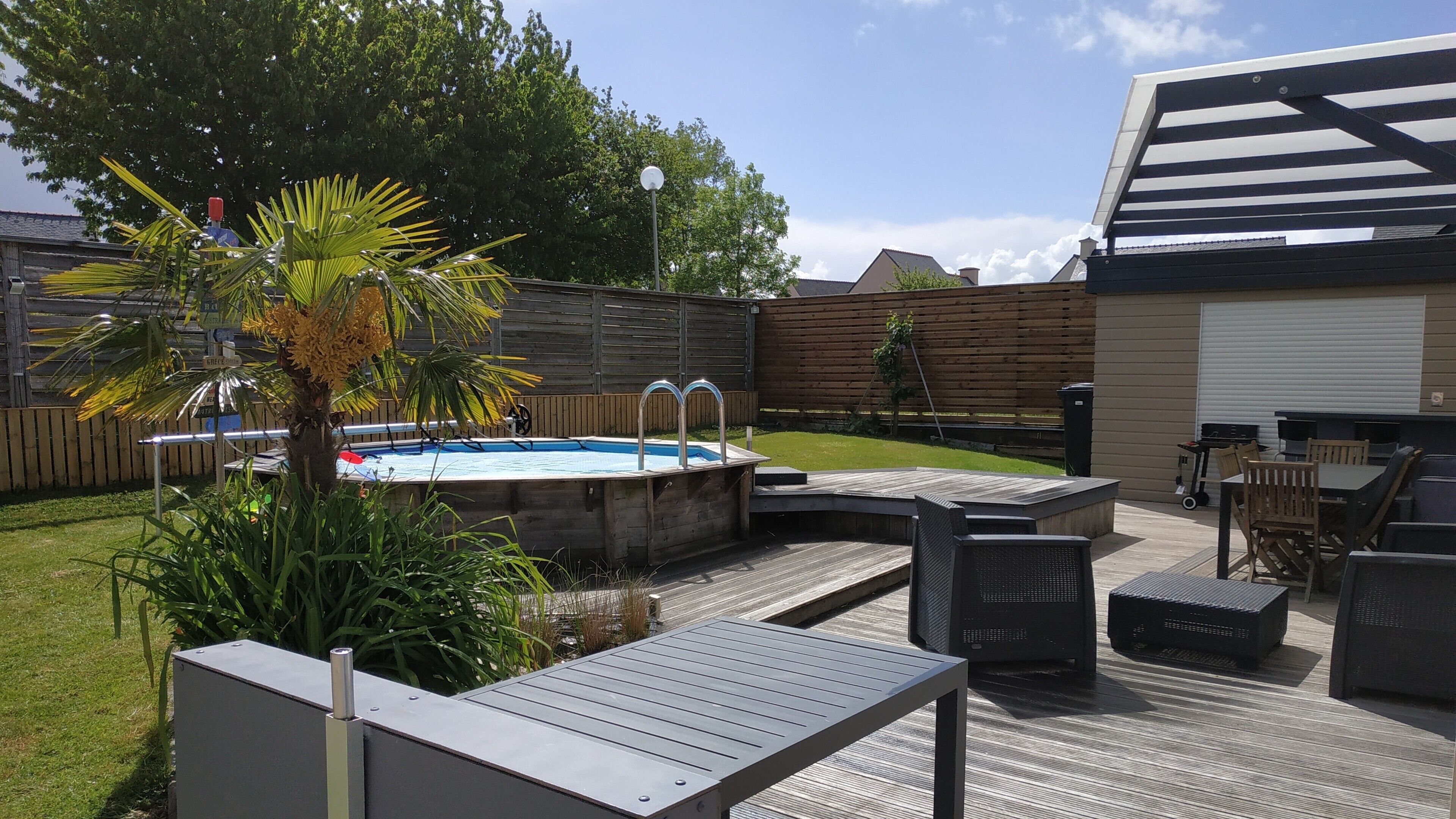 Un jardin avec un jacuzzi, une terrasse en bois, du mobilier d’extérieur et un garage.