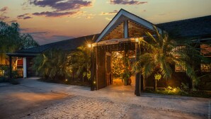 Un edificio moderno con un cartello 'Welcome', circondato da palme e un sentiero in pietra.