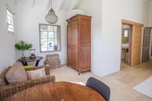 Une pièce avec un meuble en bois, des meubles en osier, une table ronde et un luminaire suspendu.