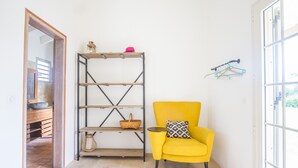 Una stanza con una poltrona gialla, una libreria in legno e una porta che dà su un bagno.