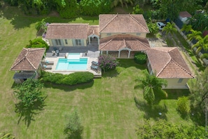 Una casa grande con piscina, varios patios y un césped bien cuidado.