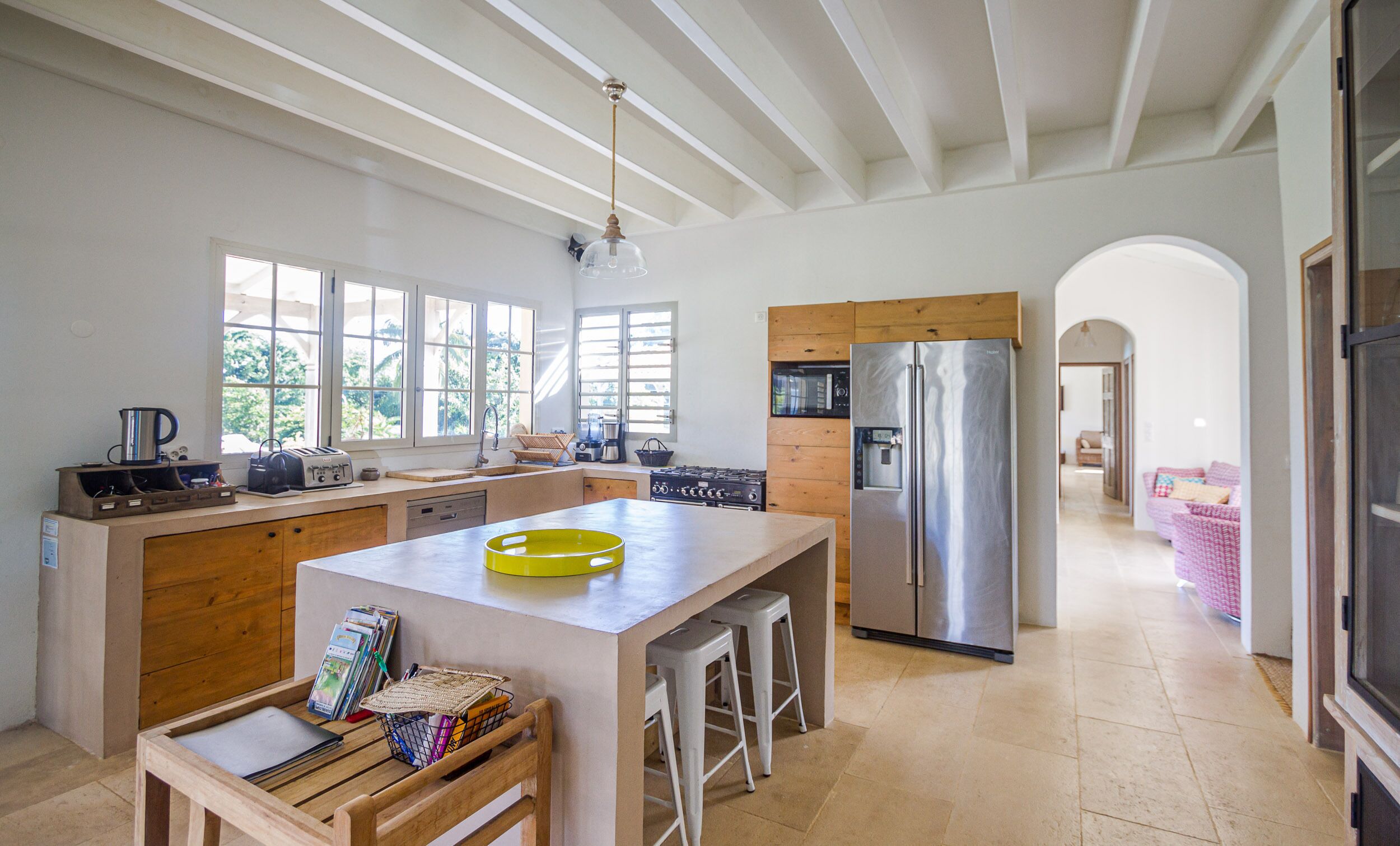 A spacious kitchen with a central island, wooden cabinetry, and a stainless steel refrigerator.