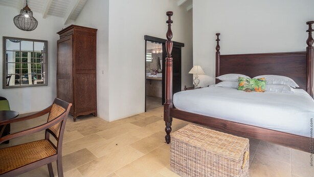 Una camera da letto con un letto a baldacchino, un armadio in legno, una sedia in vimini e un tavolo da pranzo.