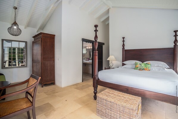 Une chambre à coucher avec un lit à baldaquin, une armoire en bois, une chaise en osier et une table à manger.