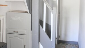 Una escalera con paredes blancas y un piso estampado, que conduce a una habitación con un radiador y un armario blanco.