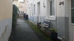 Un estrecho callejón con un banco y plantas en macetas.
