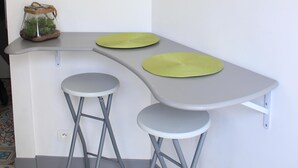 Una encimera de cocina con taburetes, un letrero con la palabra 'HOME', una foto enmarco de macarons y una planta pequeña en una cesta.