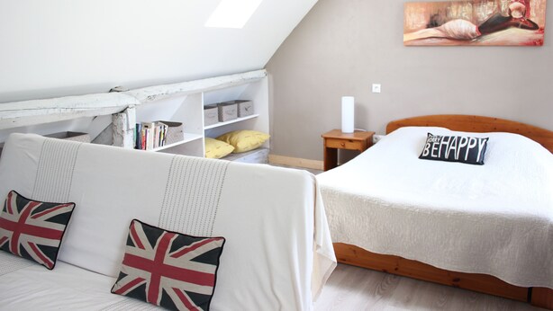 Un dormitorio acogedor con un sofá blanco, una cama de madera, una estantería y un cuadro en la pared.