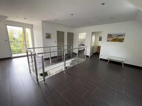 A spacious room with a balcony, a staircase, and a painting on the wall. - Villa with large capacity of reception possible departure in the afternoon (Cucq)