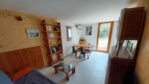 Un salon comprenant un canapé, une table basse, une bibliothèque, une table à manger avec des chaises et un grand meuble.
