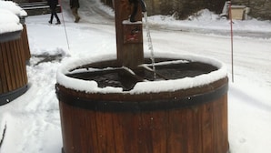 A wooden water pump in a snowy setting.