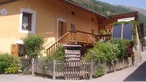 A traditional wooden building with a balcony, a staircase leading to the entrance, and a sign indicating a private parking area.