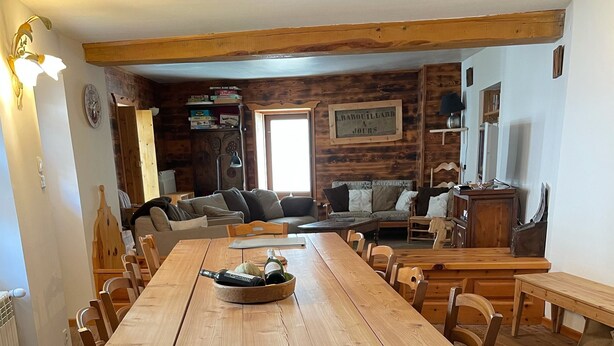 A large wooden dining table with chairs, a wooden bench, and a wooden floor.