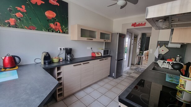 A modern kitchen with a black countertop, wooden cabinets, a refrigerator, a microwave, and a coffee maker.