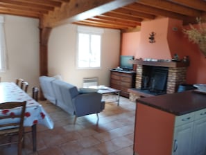 Ein Zimmer mit Esstisch, Stühlen, einer Couch, einem Kamin und einem Fernseher.
