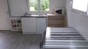 A small kitchen with a microwave, a sink, and a window with a view of trees. - Calm studio in Langueux strikes (Langueux)