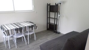 A room with a grey sofa, a striped table, and two white chairs. - Calm studio in Langueux strikes (Langueux)