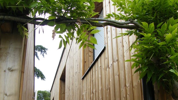 A wooden staircase leading up to a building with vertical wooden siding. - Calm studio in Langueux strikes (Langueux)