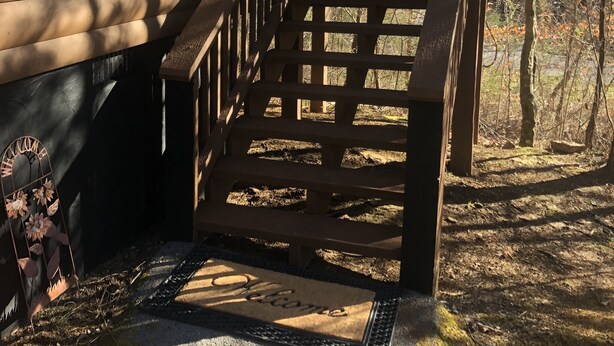 Eine Holzhütte mit einer Holztreppe, die zu einer Veranda führt.