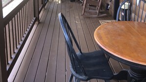 Eine Holzterrasse mit Tisch, Stühlen, einem Schaukelstuhl und einer Bank.