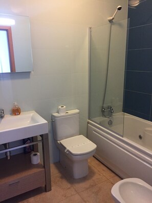 Un baño con inodoro, lavabo y ducha.
