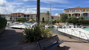A marina with boats docked, a bench, and buildings in the background. - 2 Bedroom apartment with swimming pool and underground parking (Grimaud)
