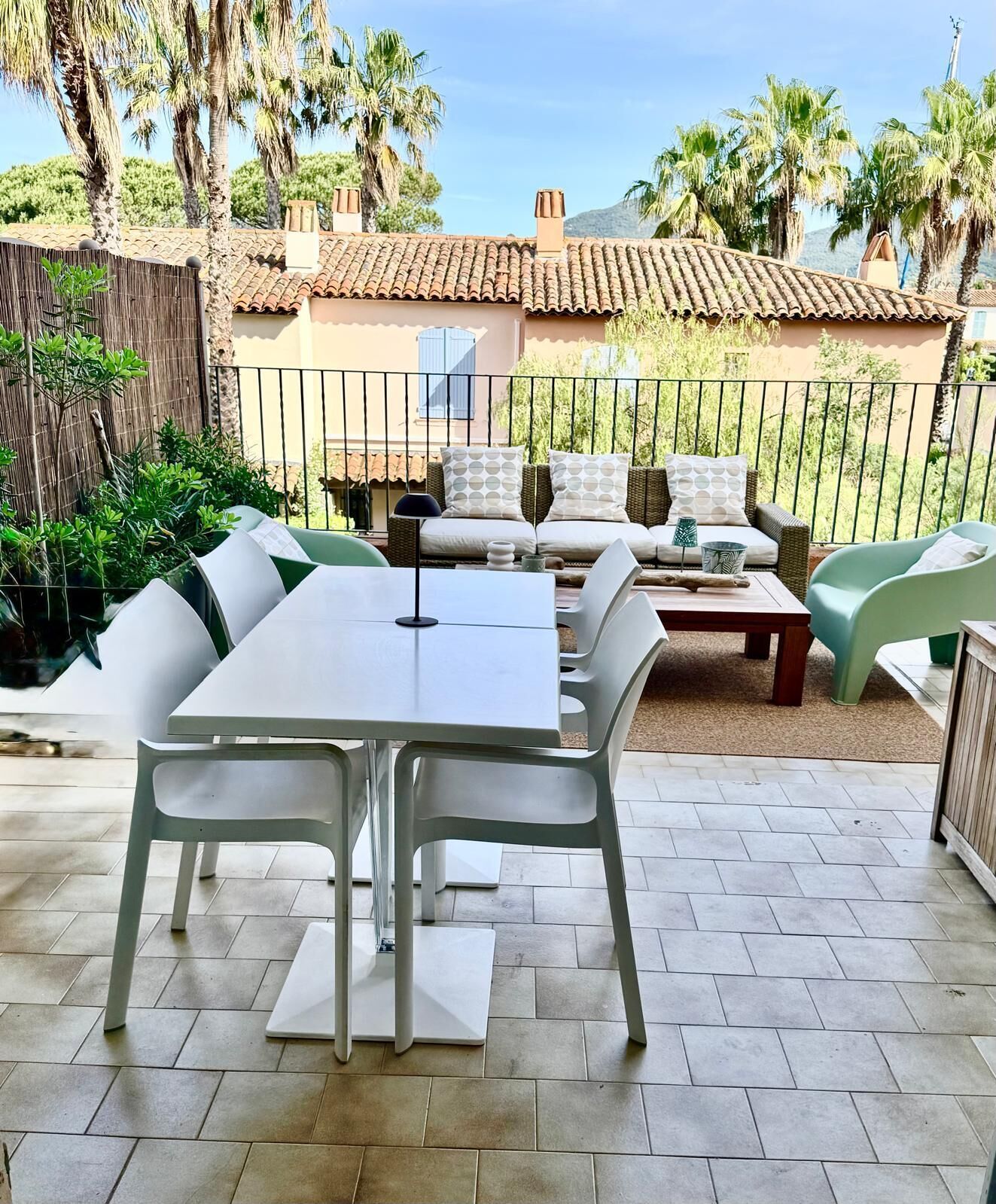 An outdoor patio with a dining table and chairs, a sofa set, and a view of a building with a tiled roof.