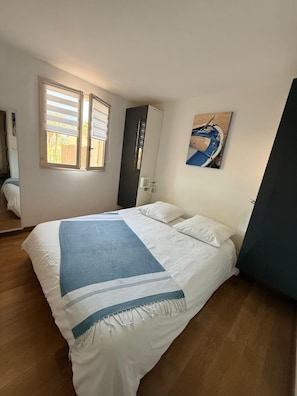 Une chambre à coucher avec un lit, une fenêtre, une armoire et un tableau au mur.