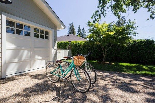 A bicycle parked in front of a garage with a basket attached to the front wheel.