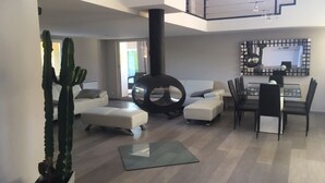 Een moderne woonkamer met een bank, een poef en een eethoek met stoelen en een tafel.