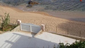 Una playa con aguas cristalinas, una orilla arenosa y una torre de salvavidas.