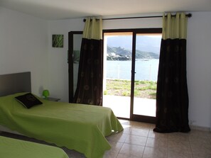 A bedroom with a bed, a nightstand, and a view of a body of water through a sliding door.