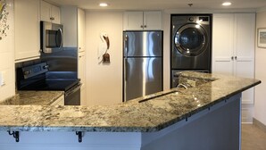 A modern kitchen with white cabinets, stainless steel appliances, and a granite countertop. - Villamare 3328, New pools, Ocean views, WiFi, Beachfront, beautifully remodeled. (Hilton Head Island)