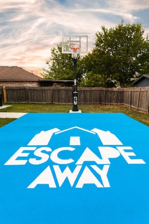 Escape to an outdoor basketball court with a hoop and sign.