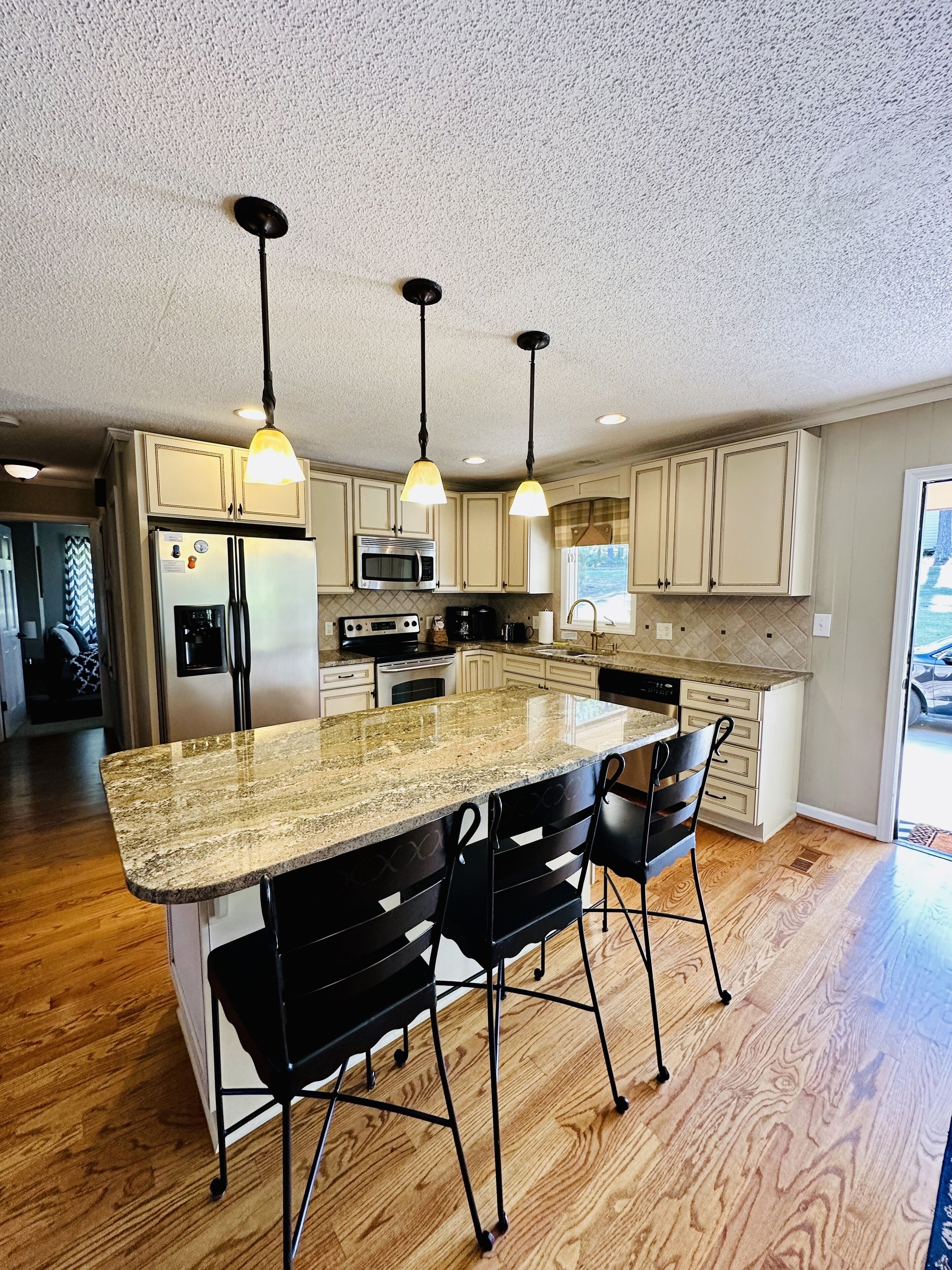 A modern kitchen with granite countertops, stainless steel appliances, and pendant lighting.