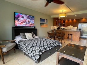 A hotel room with a bed, a TV, a dining table, and a kitchenette.